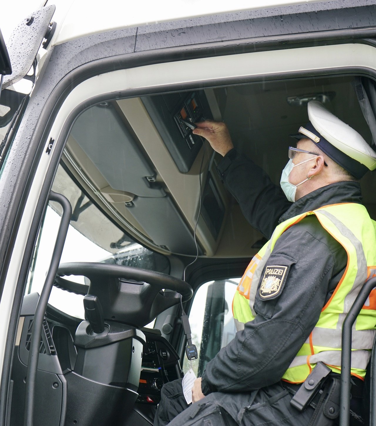 Ein Polizist kontrolliert die Lenkzeit eines Lkw-Fahrers im Führerhaus. Bild: Polizei Oberpfalz