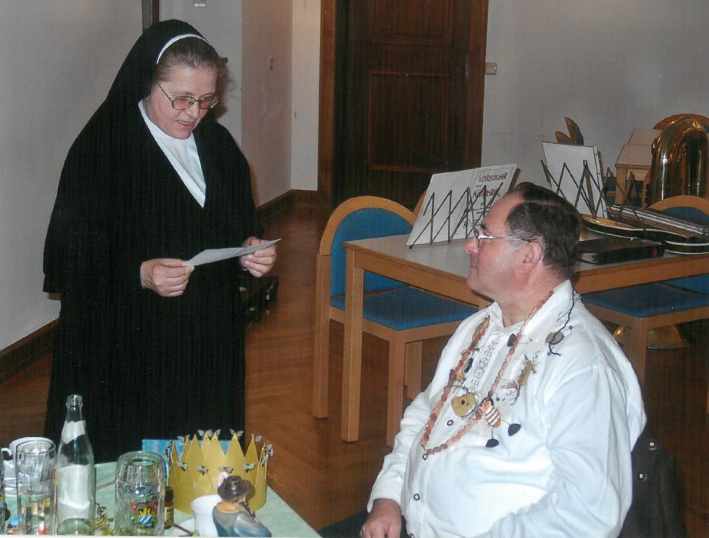 Schwester Luzentine stehend vor ihrem Bruder Georg.