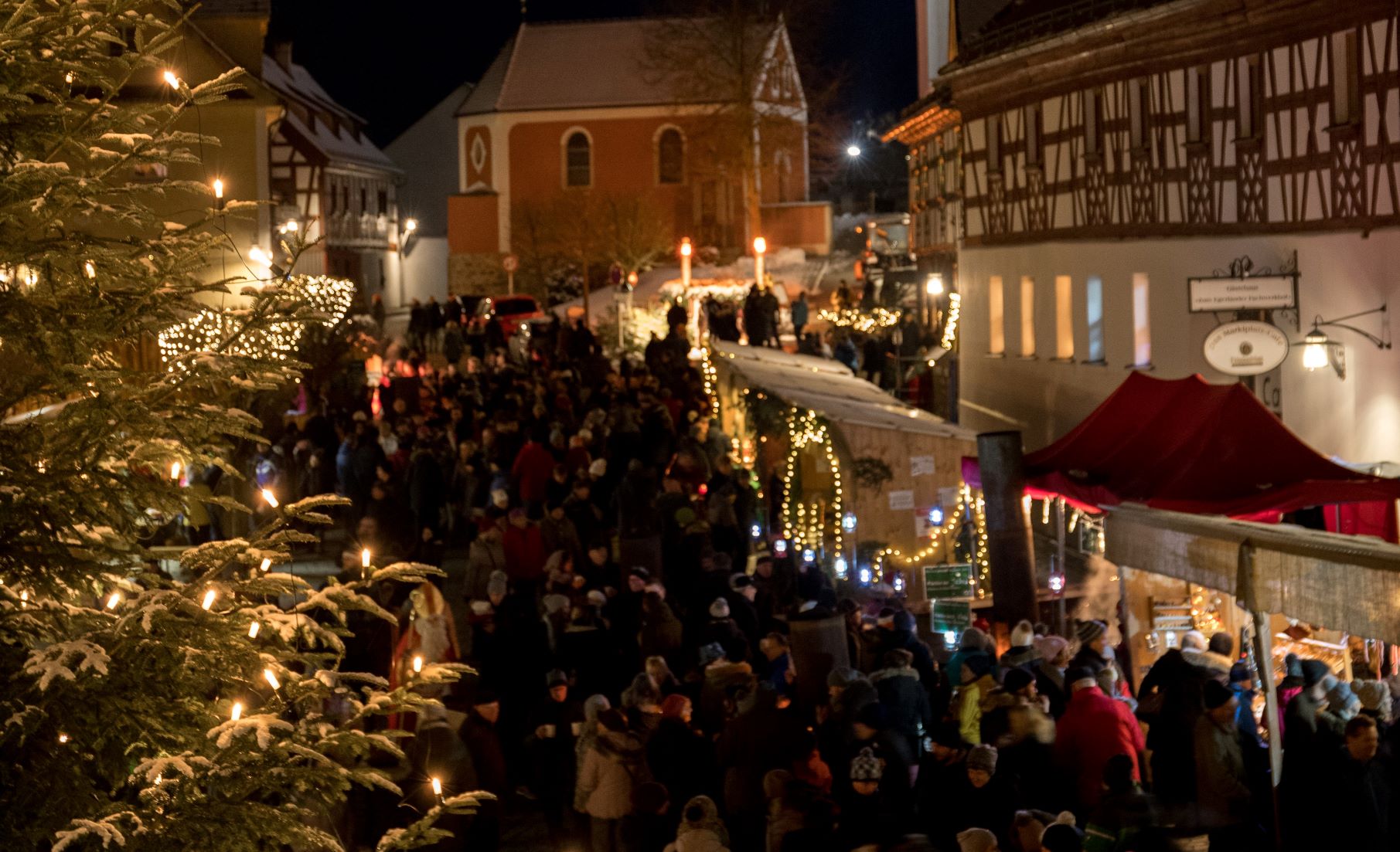 Viele Menschen besuchen die beleuchteten Stände des weihnachtlichen Kunsthandwerkermarkt in Bad Neualbenreuth.