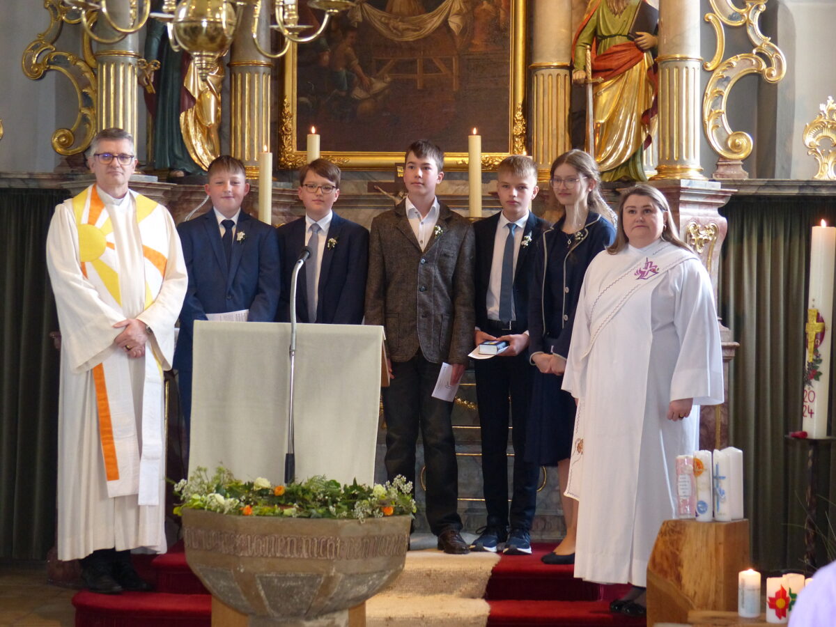 Pfarrer und Diakonin mit den Konfirmanden am Altar. Foto: Hans Meißner